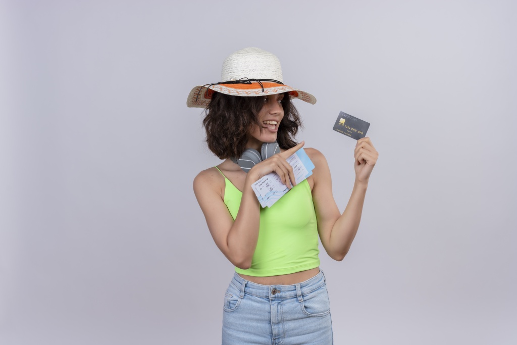 pleased-young-woman-with-short-hair-green-crop-top-headphones-wearing-sun-hat-holding-plane-tickets-pointing-credit-card-with-index-finger-white-background.jpg шляпа